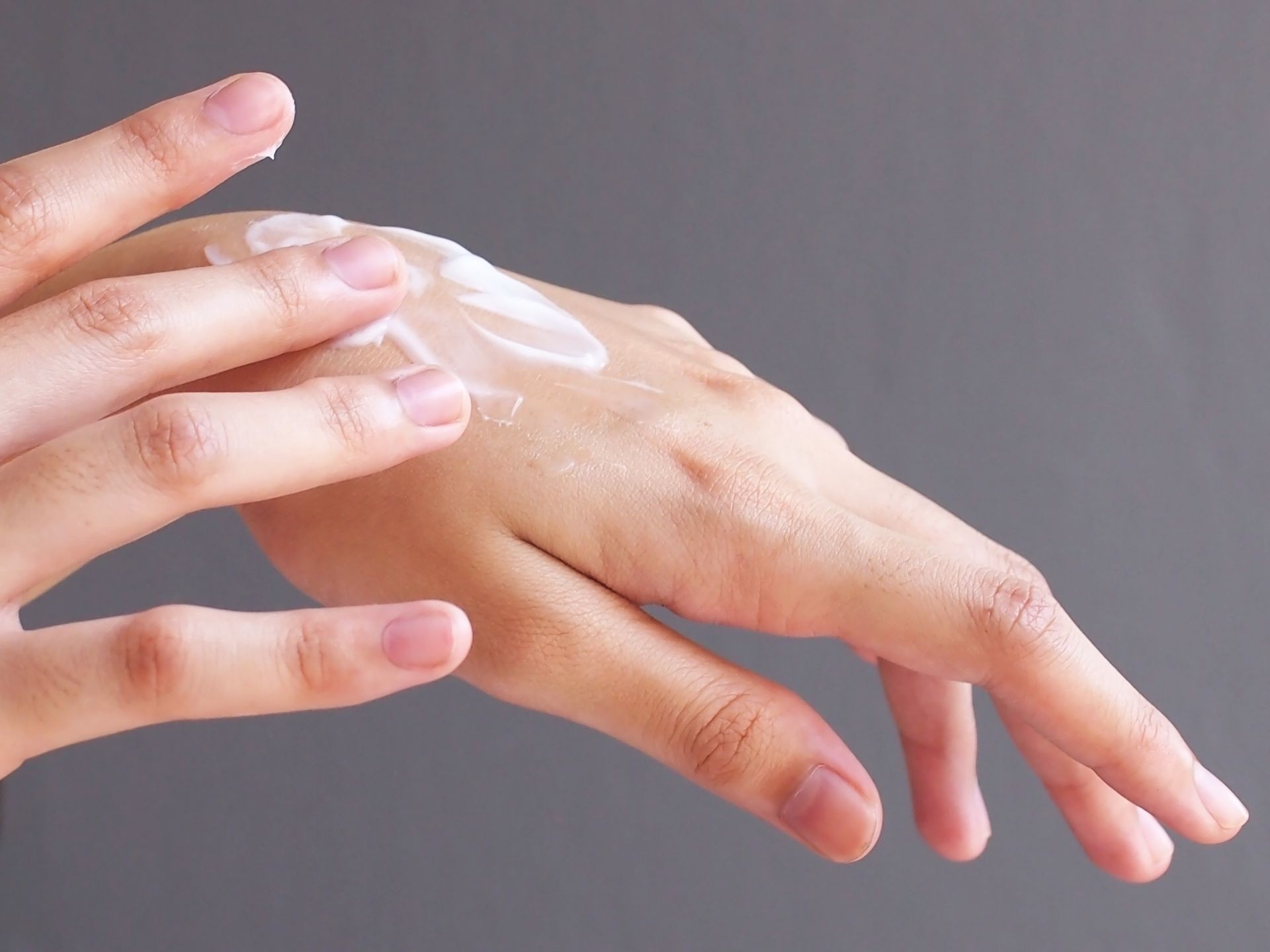 Female hands applying moisturizer lotion .
